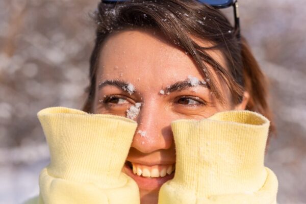 A woman gently massaging a moisturizing cream into her face to revitalize her skin, targeting areas affected by winter. The image shows how winter affects your skin, leading to dryness, and how proper skincare helps restore moisture and radiance.